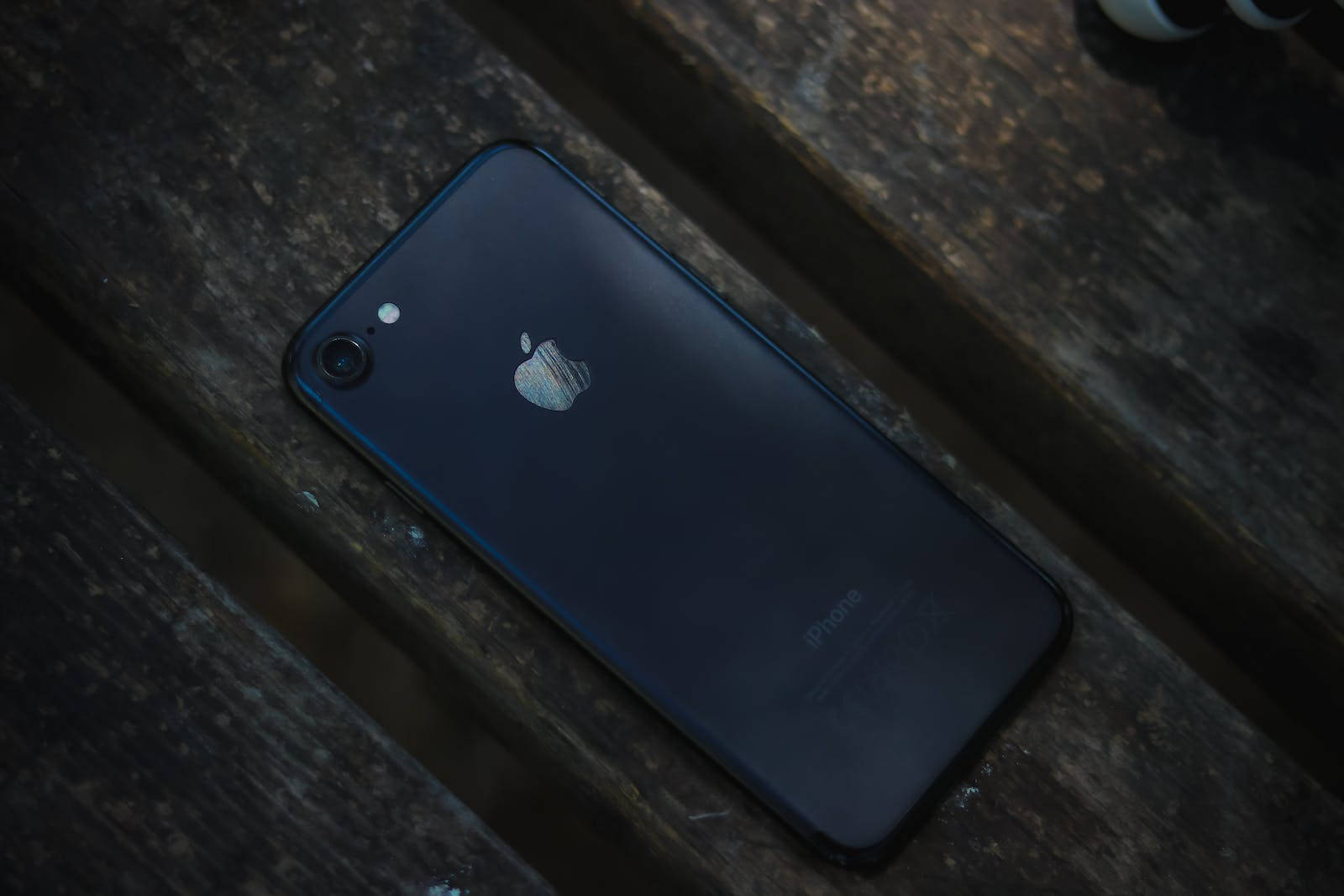 木の上に置かれたダークなiPhone 7 壁紙