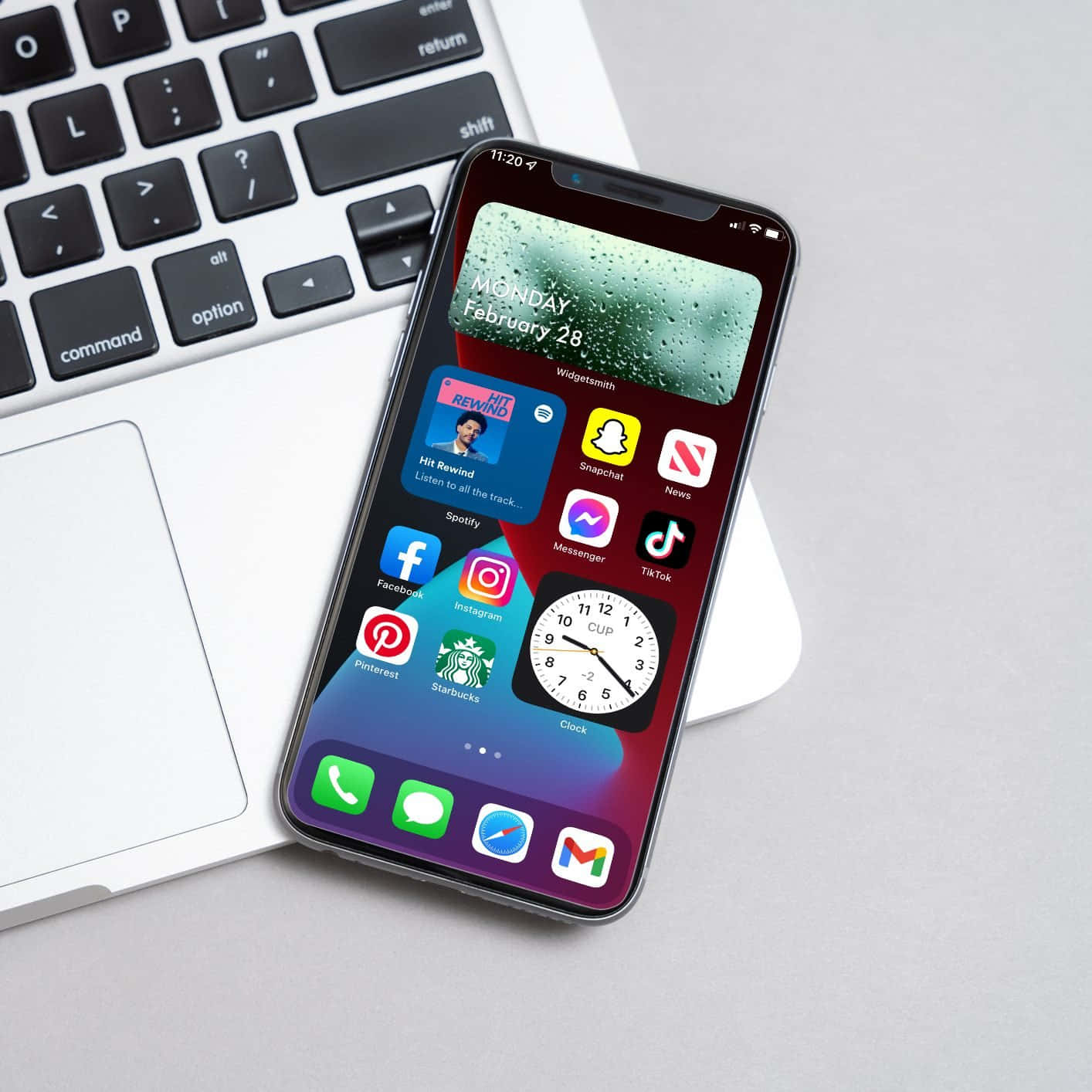アプリが表示されたiPhone XRがノートパソコンの隣に置かれている 壁紙