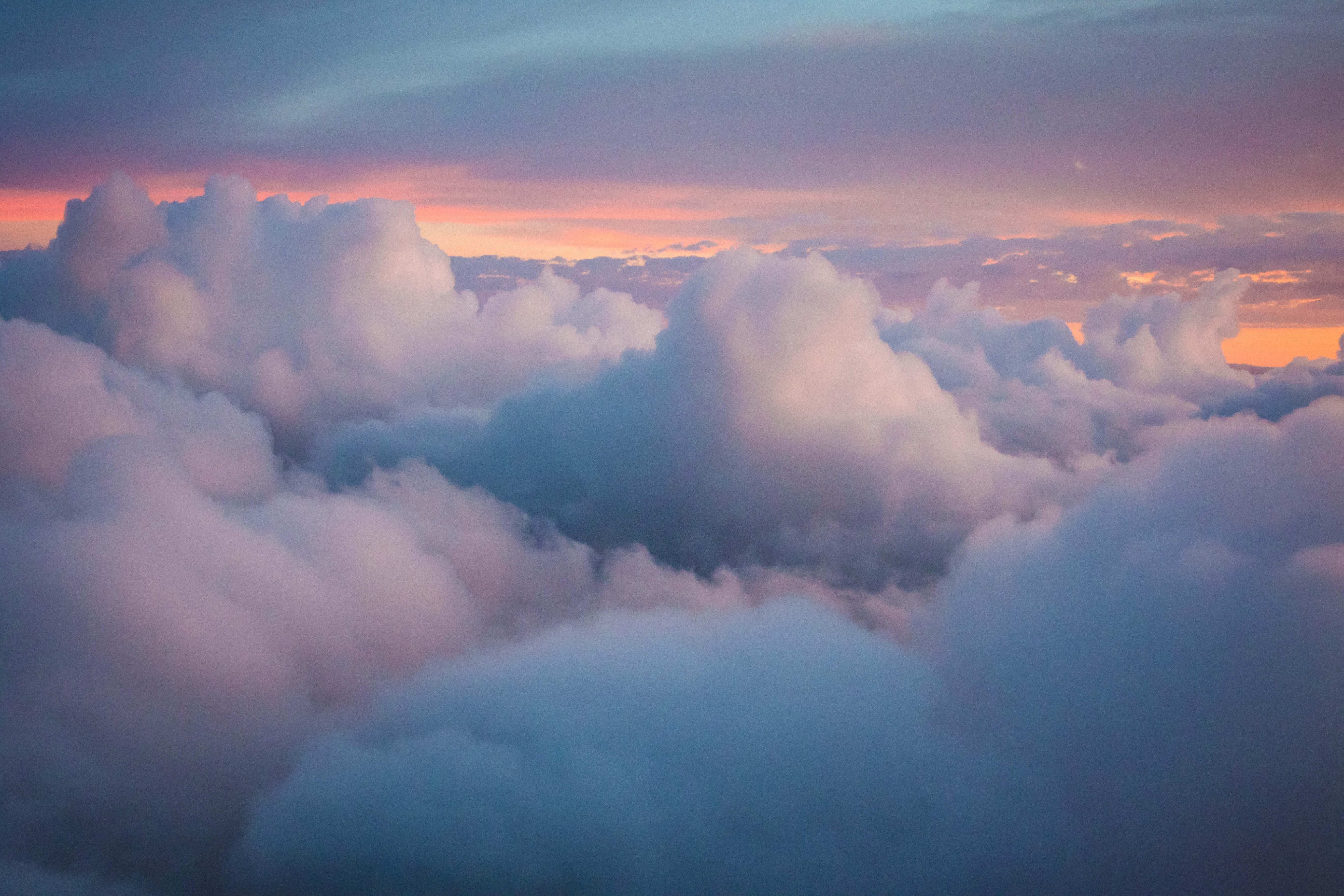 ふわふわの白い雲とオレンジ色の空の背景 壁紙