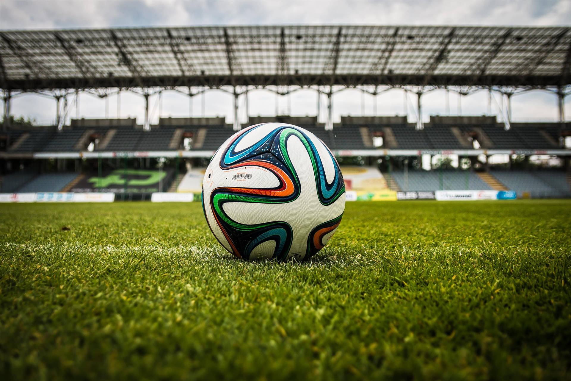 サッカースタジアムとサッカーボールの緑の芝生デスクトップ壁紙。