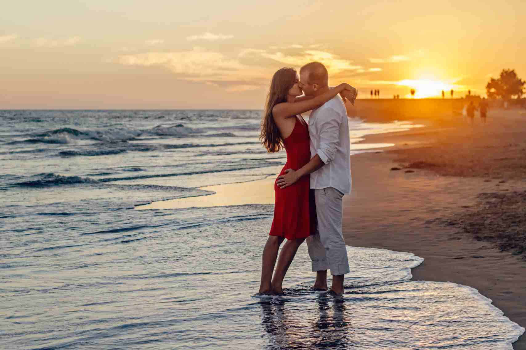 キスするカップルのロマンチックな夕焼けの写真 壁紙
