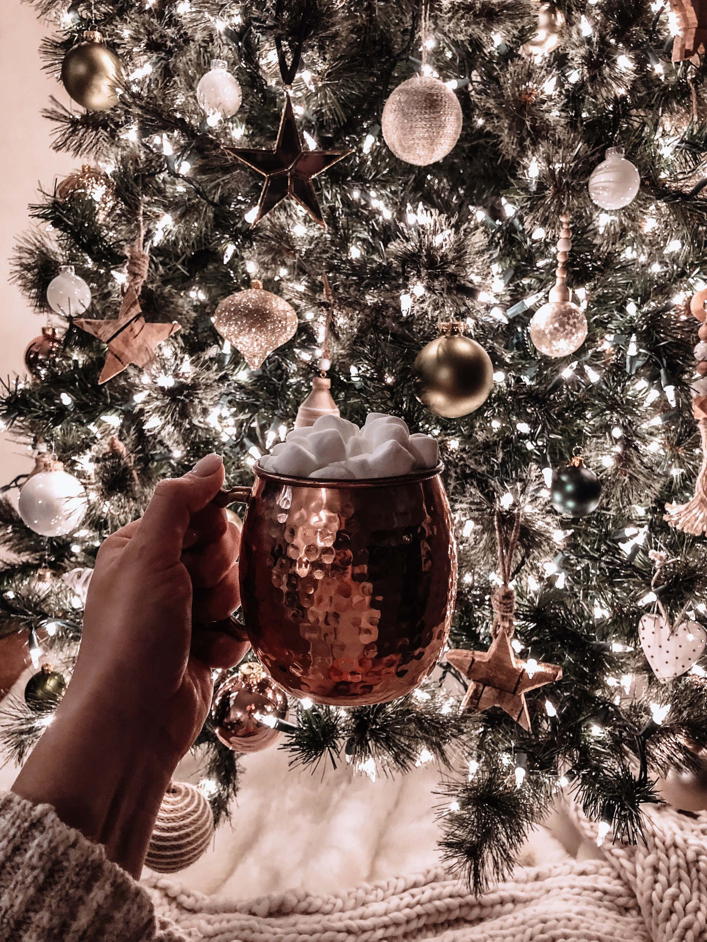 クリスマスツリーの前でコーヒーカップを手に持つ人 壁紙