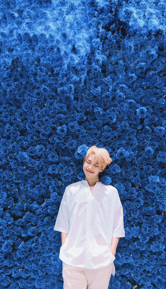青い花でいっぱいの壁の前に立つBTSメンバー。