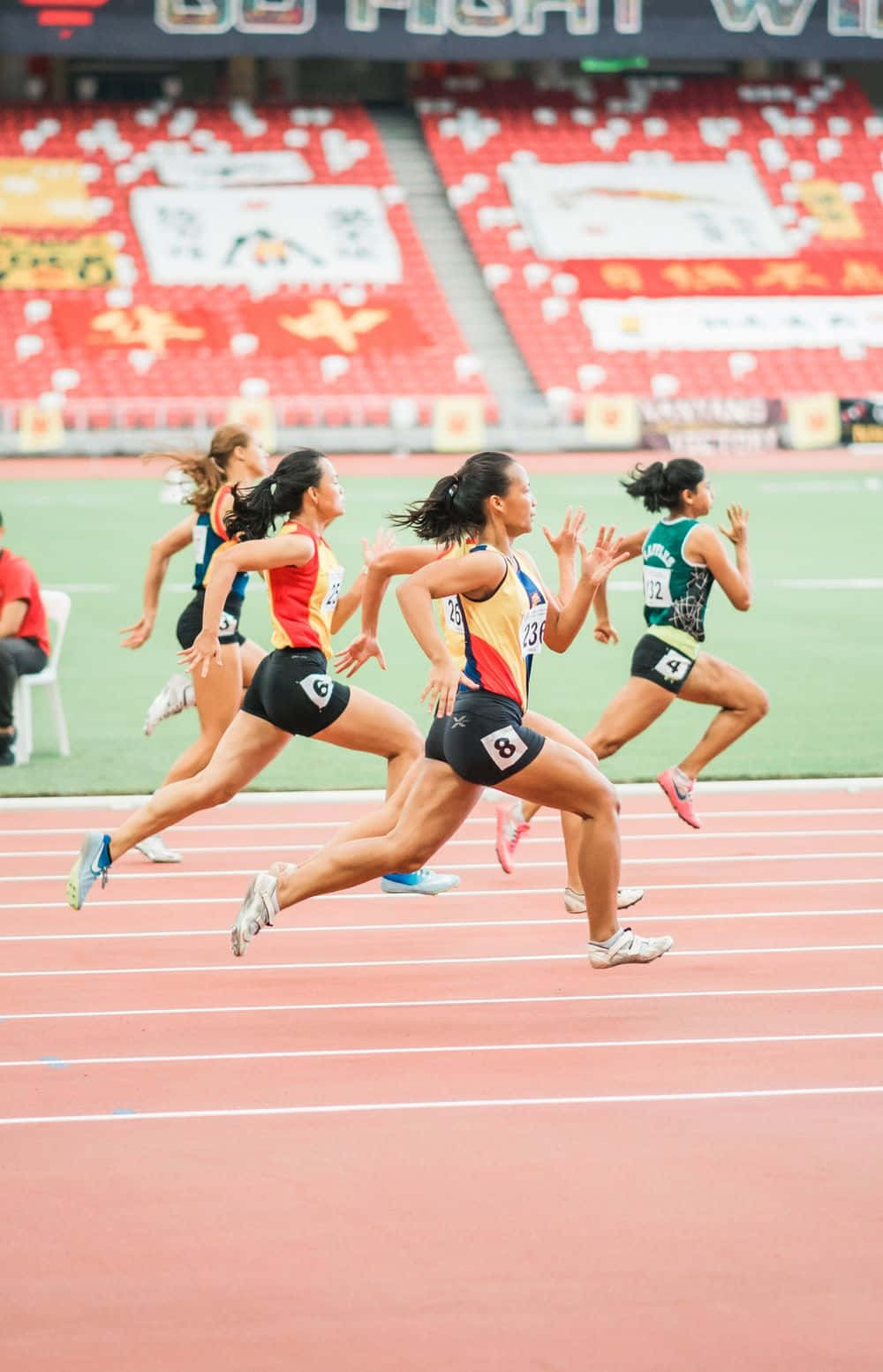 スタジアムのトラックを走る女性のグループ 壁紙