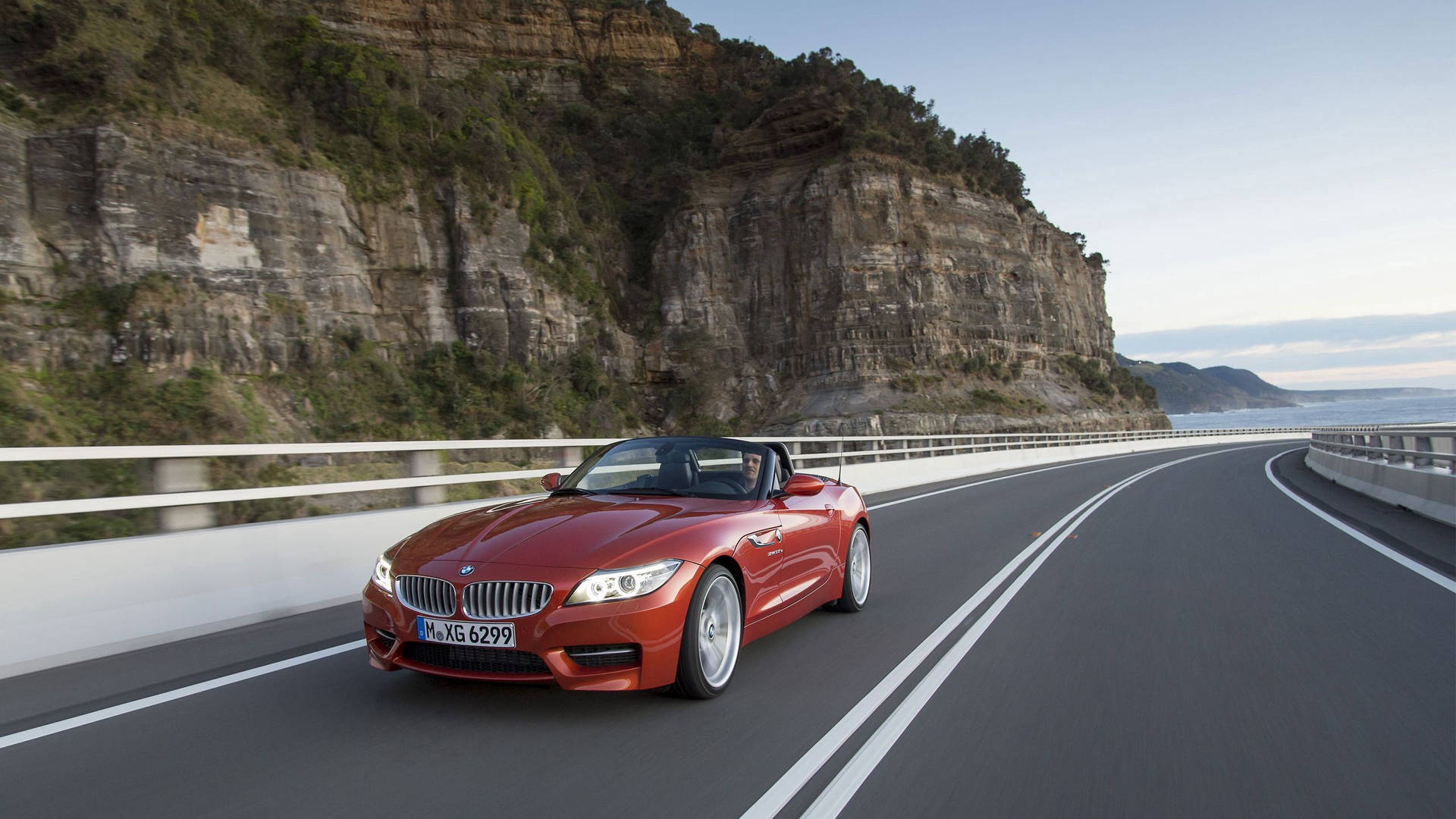 山のそばの道路を走るオレンジのBMW Z4の壁紙