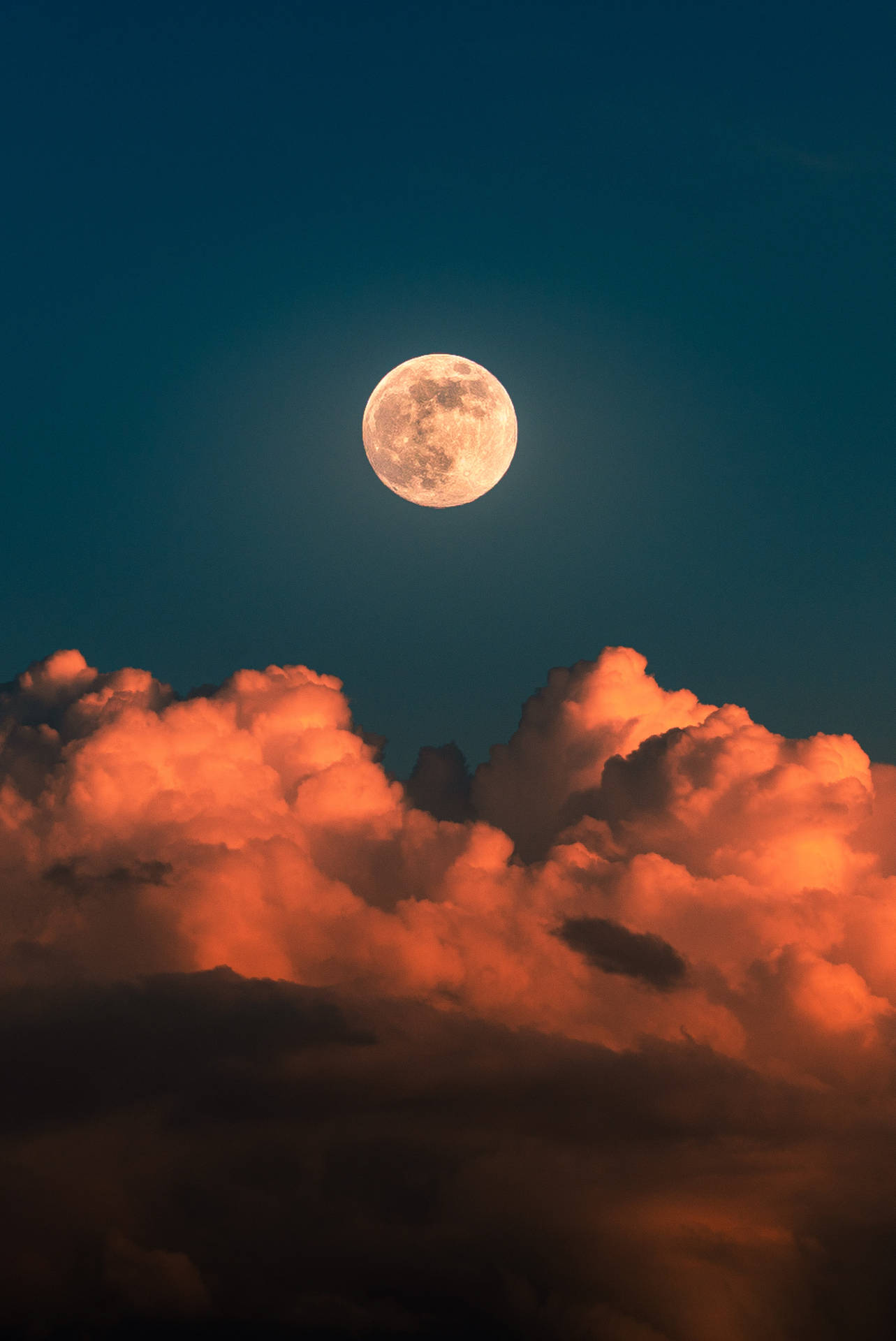 月とオレンジ色の雲が広がる青い真夜中の空。美しい夕方の景観を上から見た眺め。
