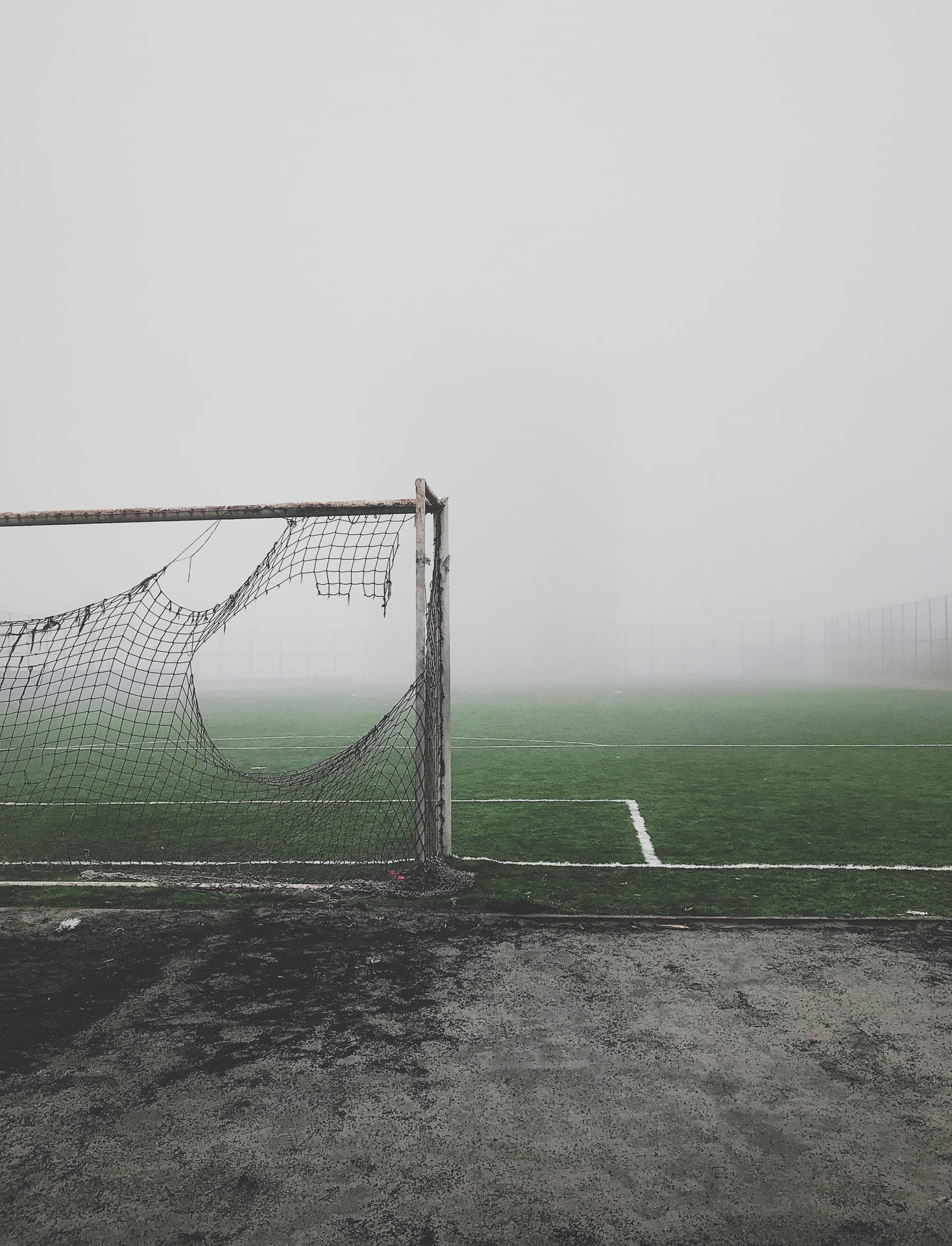 フィールドの脇にある破れたサッカーネットと霧の壁紙。