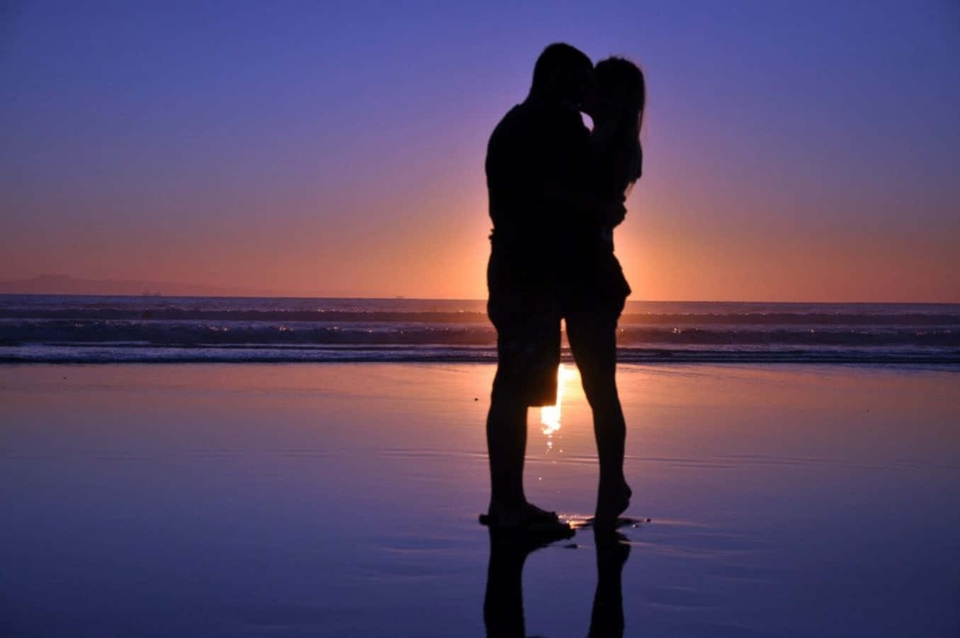 夕日の中でビーチでキスするカップル 壁紙
