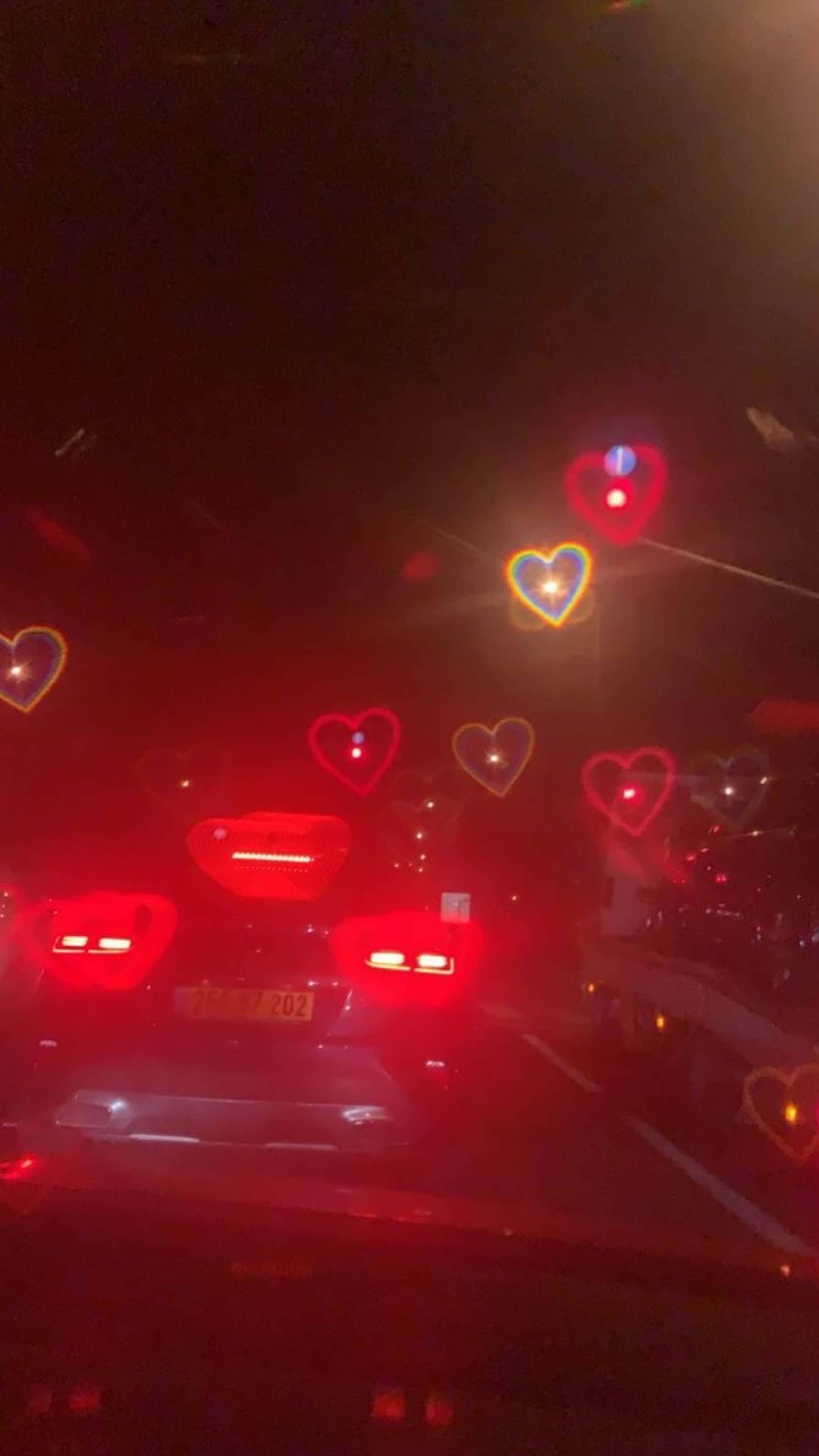 夜の道を走る車、フロントガラスにハートの装飾 壁紙