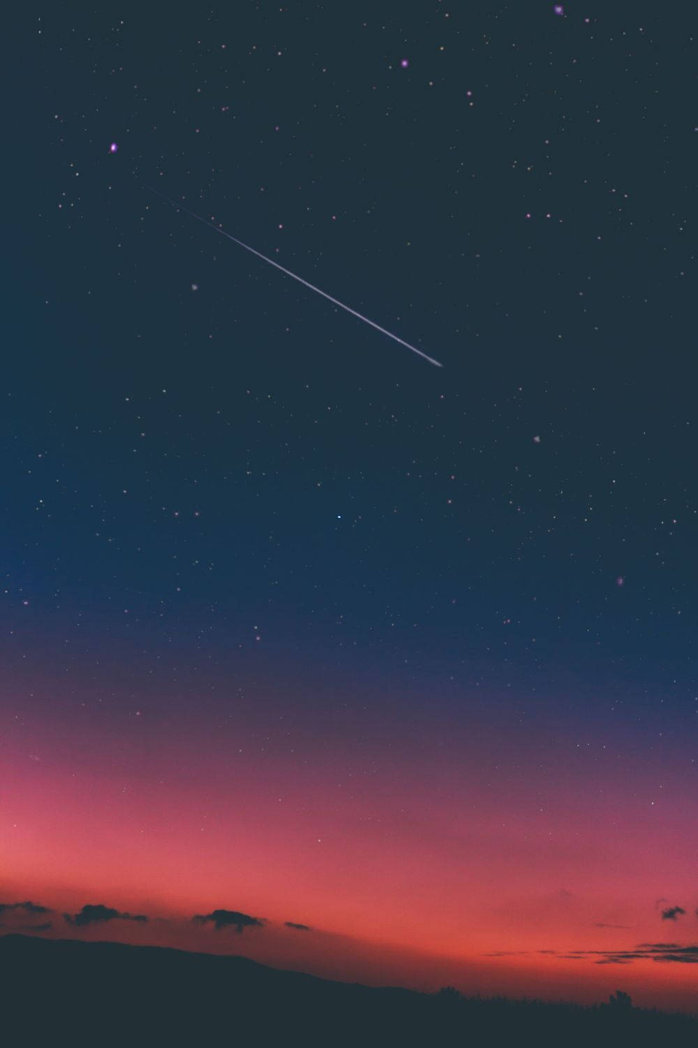 ピンクの暗い夜空に流れ星と幻想的な空。ピンクと青の空が広がるドラマチックで魔法のような天と星々。