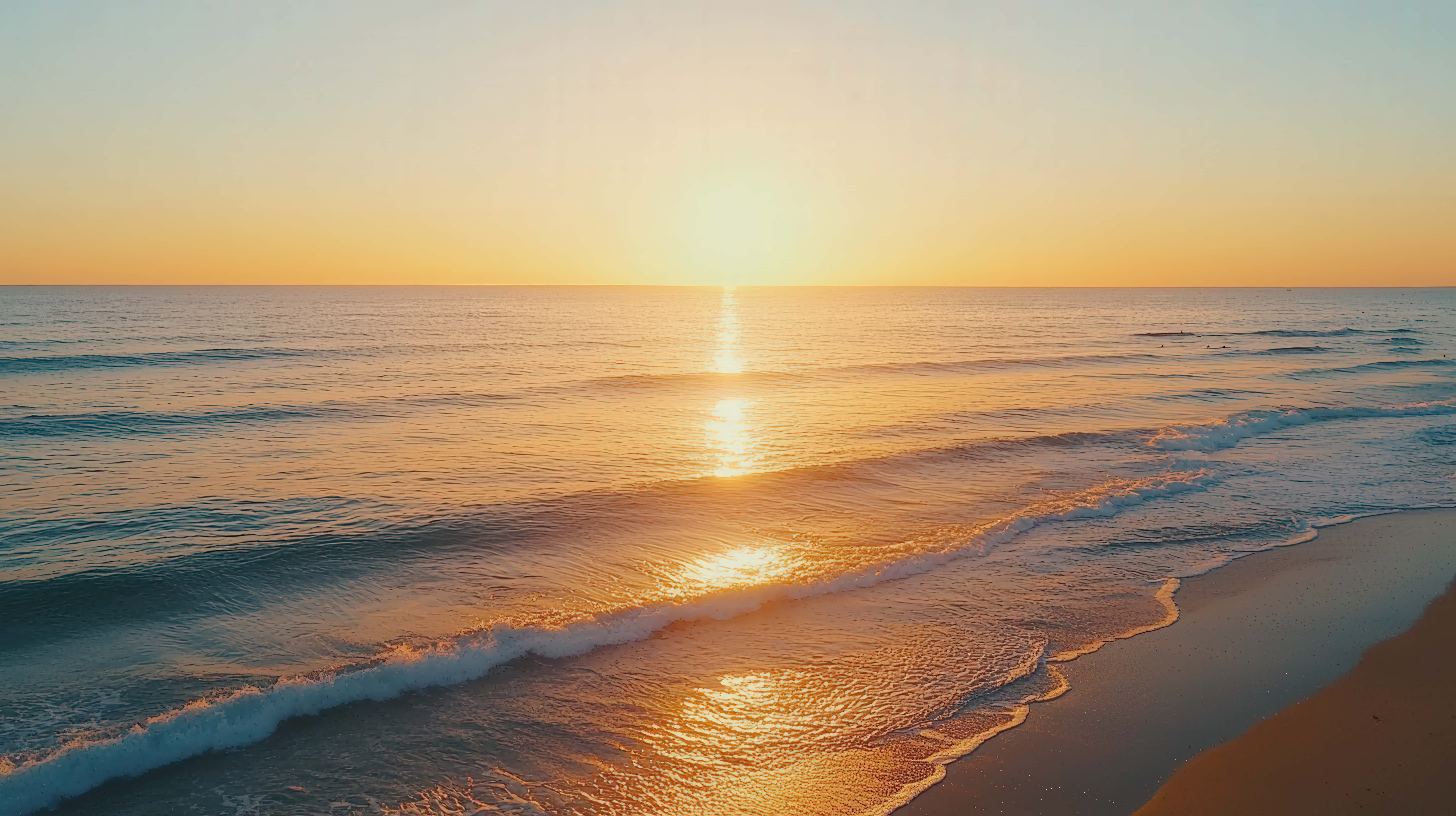 息をのむような海の夕日、穏やかな波に映る金色の反射と静かなビーチの水平線 壁紙