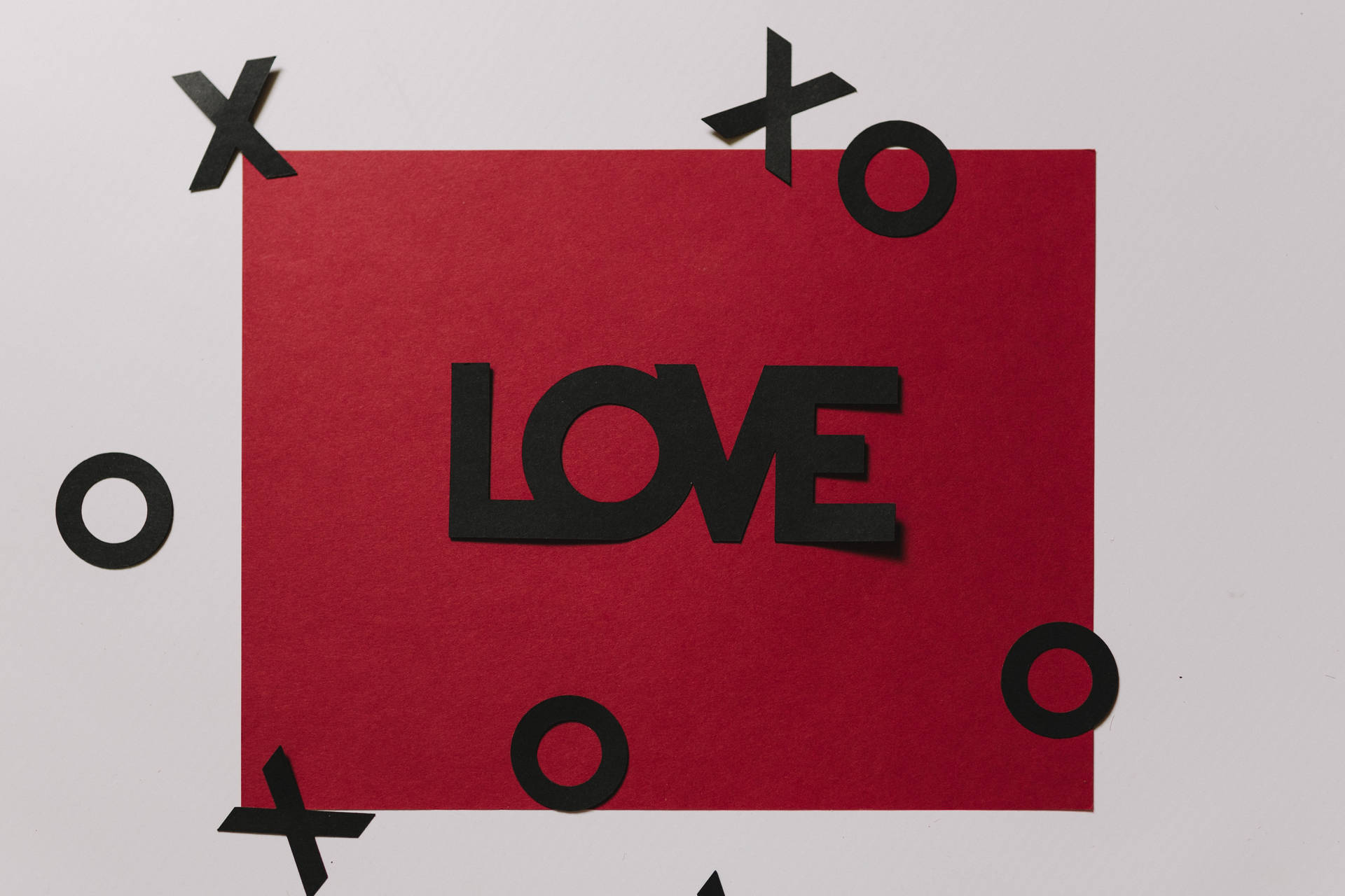 白い表面に「Love」と黒字で書かれた赤いラブレターと、浮かぶXOXOの切り抜き。