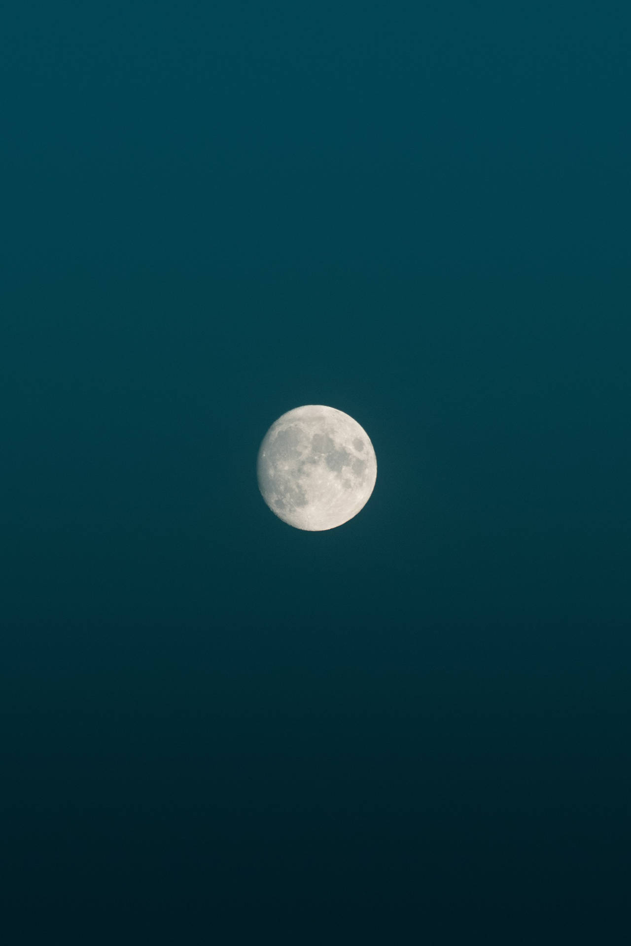 真夜中の青いミニマルな空に浮かぶ満月の明るさ。月とその表面の模様。
