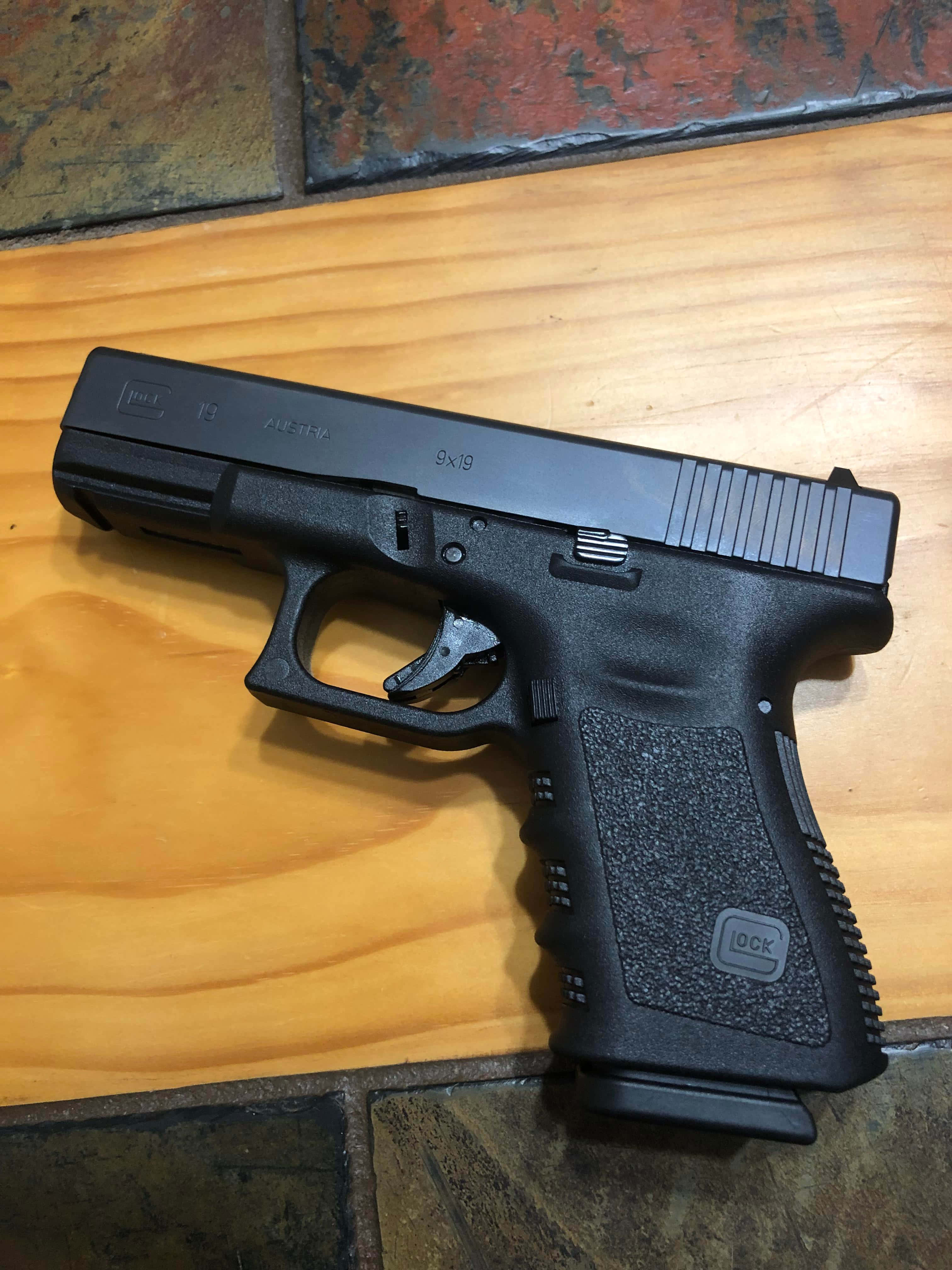 木の床に置かれた黒いグロック拳銃 壁紙