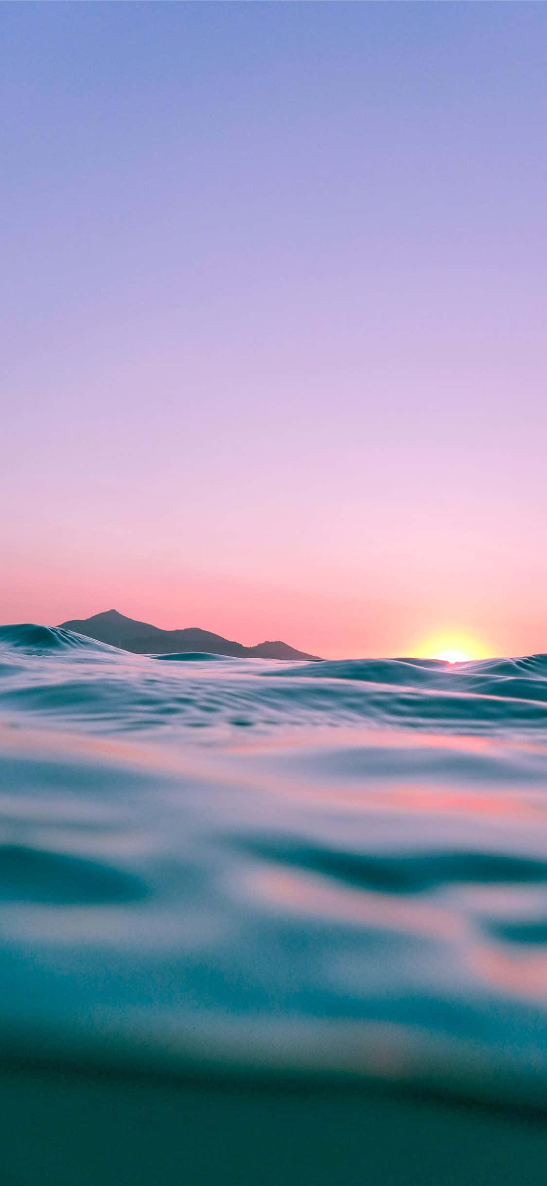 波と山々のある海の夕日 壁紙