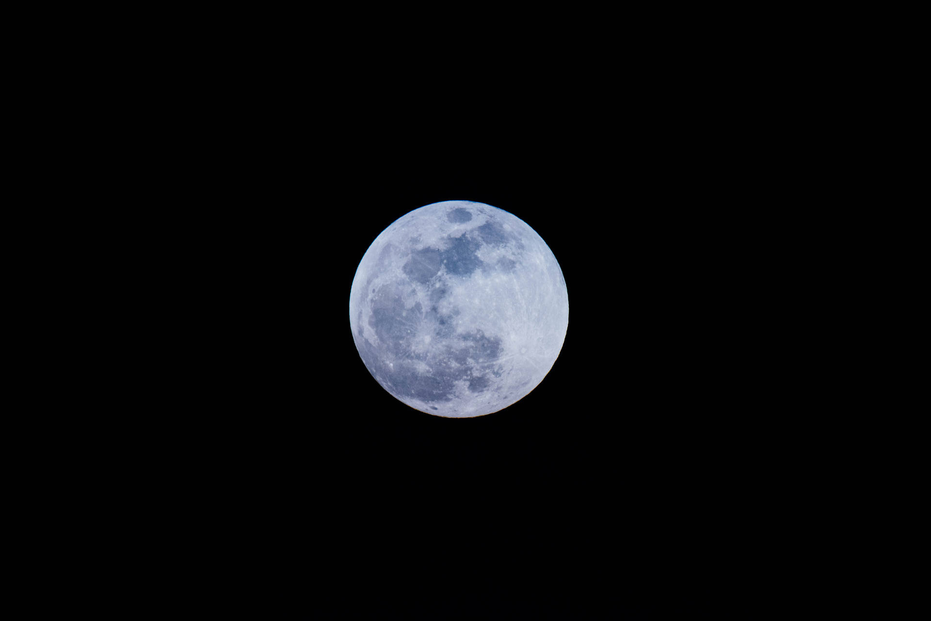 真夜中の空に明るく輝く満月。月の表面にクレーターが見える。
