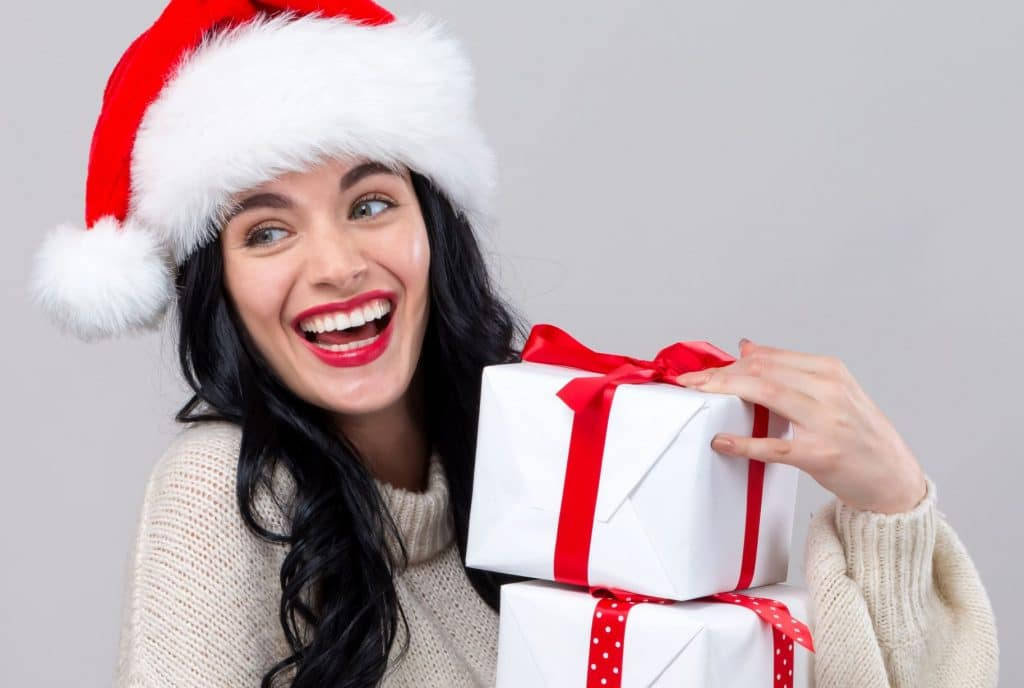 美しい少女がクリスマスプレゼントを抱える 壁紙