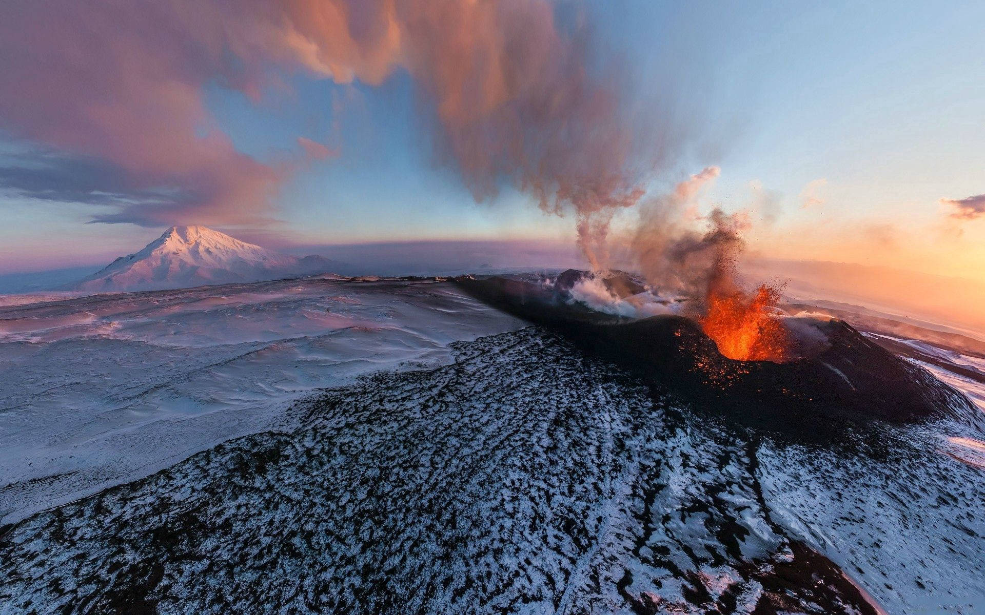 夕日の中、煙と火を噴き出す火山