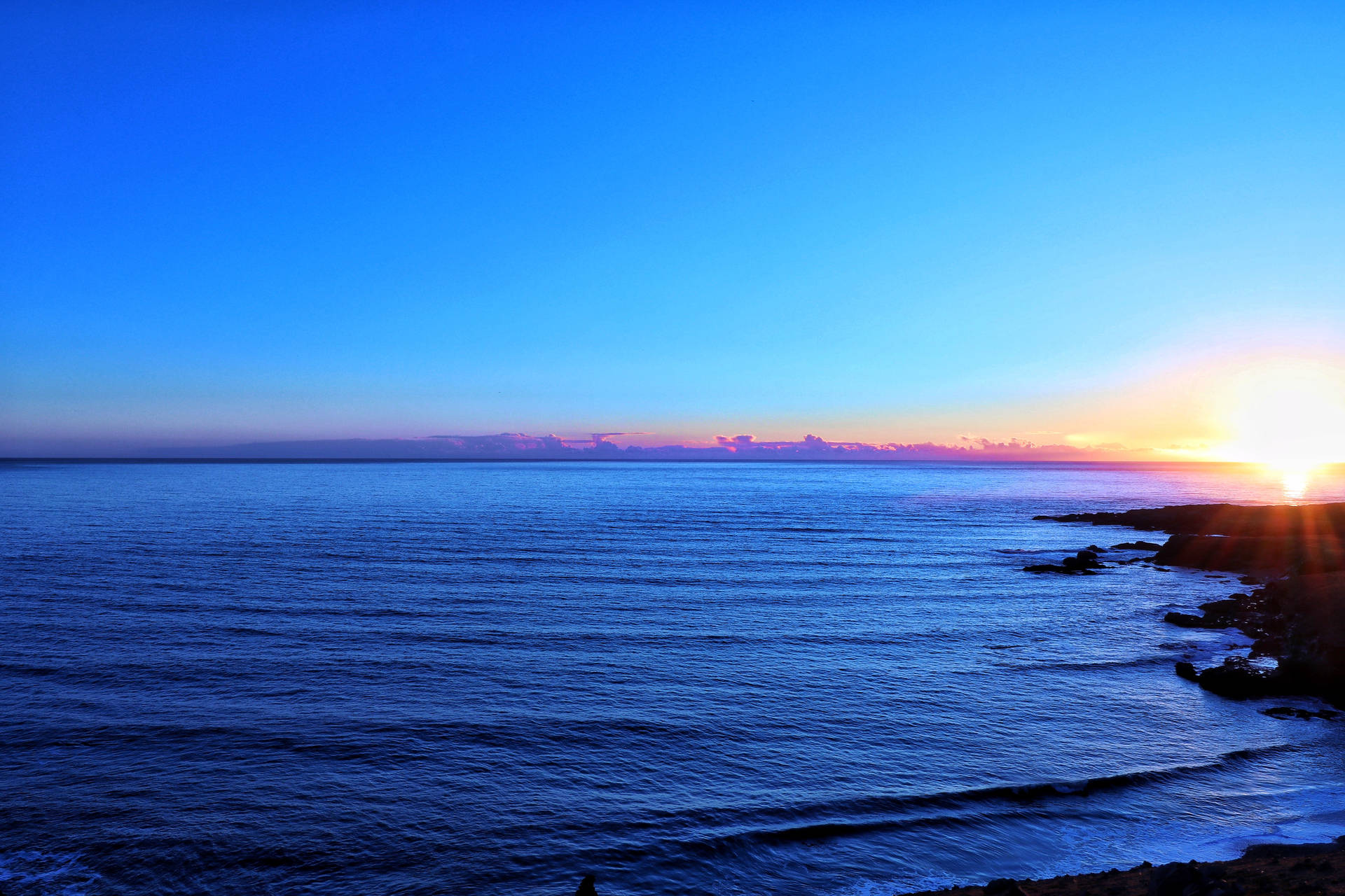 夕日の中、水平線を見せる青い海と空。