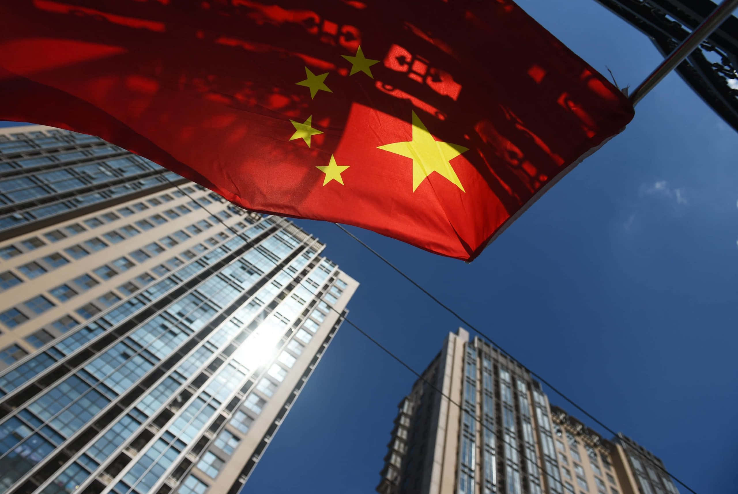 高層ビルの前ではためく中国国旗 壁紙