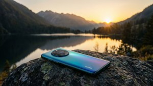 岩場に置かれたHuaweiのスマートフォンが、夕日に染まる山々と湖を見下ろす、静寂な風景。