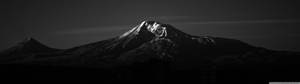 上部に白い反射がある超広角の黒い山 — 3840x1080 壁紙