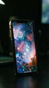 暗闇の中でギャラクシーの壁紙を光らせるiPhone 17の画面。