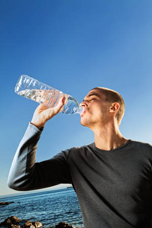 ボトルから水を飲む男性