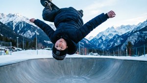 スケーターボーイが雪山のハーフパイプで360フリップを決める様子。