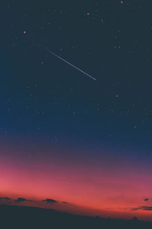 ピンクの暗い夜空に流れ星と幻想的な空。ピンクと青の空が広がるドラマチックで魔法のような天と星々。