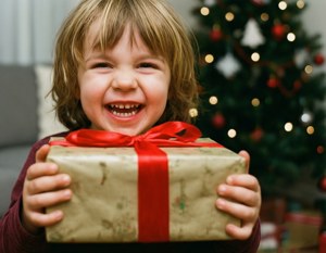 クリスマスプレゼントを抱えた幸せな子どもが、喜びと期待に満ちている様子。 — クリスマスプレゼント 壁紙
