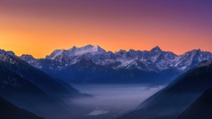 息をのむような超広角の眺め、夜明けの雪を頂いた山々と霧の谷間。
