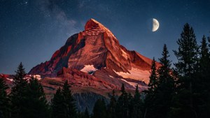 月明かりに照らされた壮大な赤い山頂と、その上に広がる星空の夜景色。