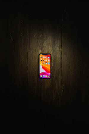 木の床に置かれたiPhone Xs Maxの壁紙