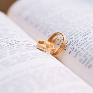 本の上に置かれた金の結婚指輪 — Huawei nova Flip S 壁紙