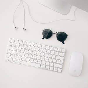 白いApple MACセットアップ（iMAC、ワイヤレスキーボード、マジックマウス、イヤホンを含む）のミニマリスト壁紙