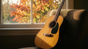 窓辺に置かれたギターと秋の葉、温かな光。 — 音楽 美学 壁紙
