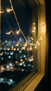 夜の街のボケ味を背景に、窓辺に飾られたフェアリーライト。 — クリスマス エステ 壁紙