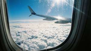 飛行機の窓からの空の眺め。眼下に雲海、頭上に青空が広がる — 空の眺め 壁紙